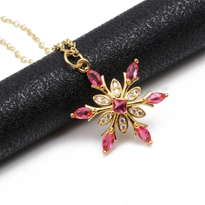 Macro shot of 18K gold plated snowflake pendant with red zircon and clear gems