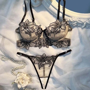 Flat lay of gray lace mesh bra set with black floral embroidery and pearl accents