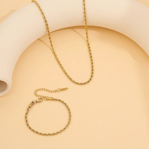 Gold twist rope necklace and bracelet set with adjustable lobster clasp on beige backdrop