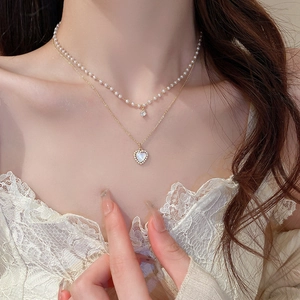 Close-up of double-layer necklace featuring a pearl choker and gold heart-shaped pendant