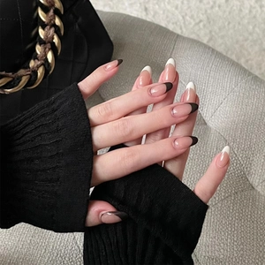 Close-up of elegant black and white French tip almond press-on nails on model hands