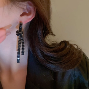 Detail of long black tassel earrings with a knotted design and cubic zirconia crystals
