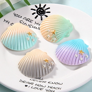 Detailed view of colorful resin shells with faux pearls and golden starfish on a white plate