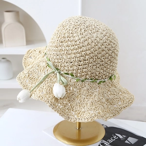 Detail of hand-woven straw hat with scalloped wide brim and white tulip pendant