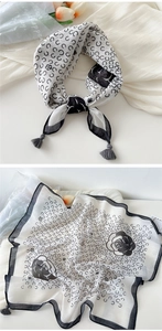 Detail of white cotton linen scarf featuring black floral prints and elegant grey tassels