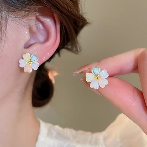 Macro detail of acrylic floral earring with iridescent petals and golden bead center