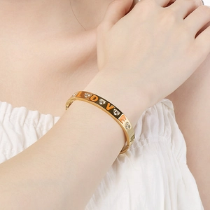 Detail of LOVE gold plated bracelet with orange enamel and sparkling crystals on wrist