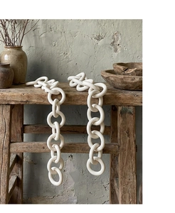 Close-up of white matte ceramic chain link decor draped on a rustic wooden bench