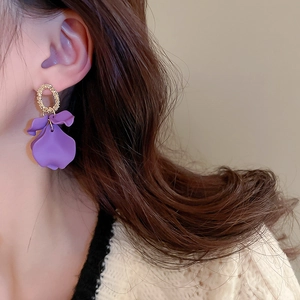 Detailed shot of purple matte petal earrings with golden textured rings on model