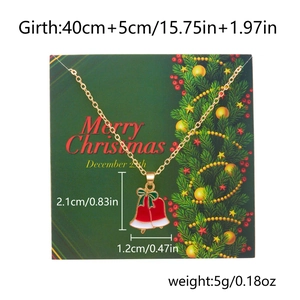 Close-up of a festive Christmas bell necklace with red enamel and Merry Christmas card