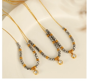 Detail of beaded pendant necklace with grey crystals and gold accents on a white background