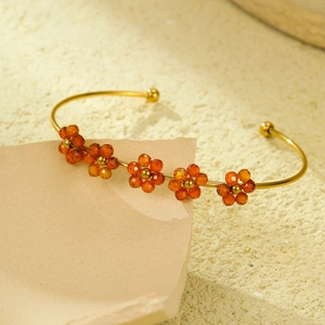 Macro di bracciale rigido in acciaio dorato con fiori di zirconi color arancio
