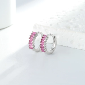 Détail de boucles d'oreilles argentées avec zircons roses en taille baguette