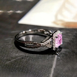 Détail de bague avec pierre carrée rose, sertissage halo et anneau croisé