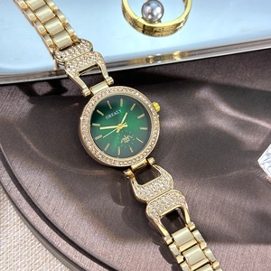 Vue macro de la montre à quartz dorée avec cadran vert dégradé et lunette ornée de cristaux