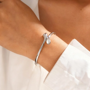 Dettaglio del bracciale ovale incrociato in argento al polso con finitura liscia