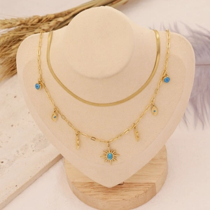 Detail of bohemian gold double-layer necklace with blue evil eye and sun pendants