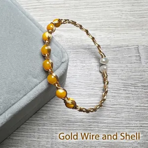 Detailed shot of 14K gold wire hand-wrapped bangle with yellow shells and white pearls