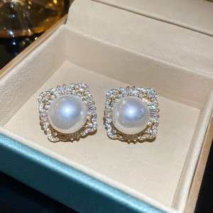 Detailed view of square pearl stud earrings with zircon halo in a luxury jewelry box