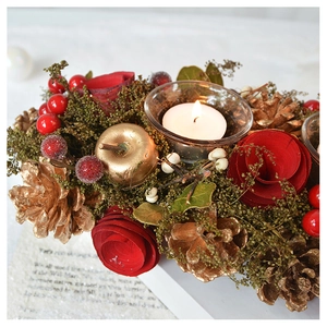 Close-up of Christmas candle holder with red roses, pine cones and golden apples