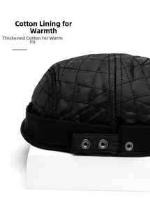Detail of black quilted docker cap with diamond pattern and metal rivet strap