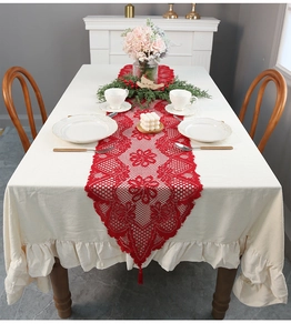 Detail of red lace Christmas table runner with tassels and crochet floral patterns