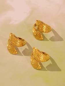 Detailed macro view of three golden leaf rings with textured veins and open design