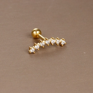 Detailed close-up of curved gold piercing stud with seven sparkling cubic zirconia stones