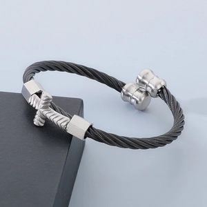 Detailed shot of dark braided cable bracelet with silver cross accent on black stand