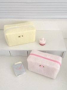 Detail of floral knit makeup bags in pastel pink and cream with rose accent and zipper