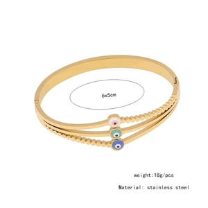 Detail shot of a golden stainless steel triple-layer open bangle with Evil Eye charms