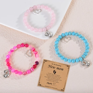 Three beaded mom bracelets in pink and blue with heart and baby footprint pendants