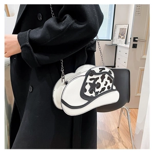 Detail of white cowboy hat shaped crossbody bag with cow print and star accent