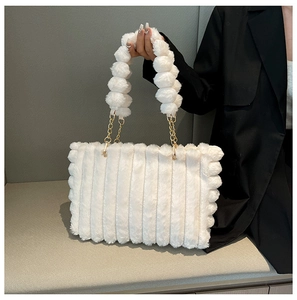 Detail of white plush tote bag featuring vertical stripes and pompom bead handles