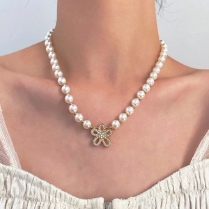 Detail view of model wearing elegant pearl necklace with rhinestone flower pendant