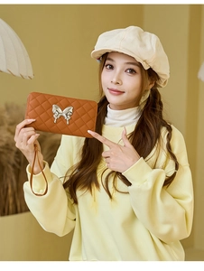 Detail of caramel quilted wallet featuring a metallic silver bow and leather wristlet