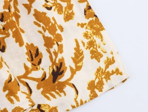 Détail de l'imprimé feuilles brunes sur tissu crème pour robe de style bohème chic