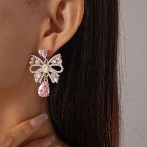 Macro de boucles d'oreilles nœud argenté avec cristaux roses en cœur et goutte sur mannequin