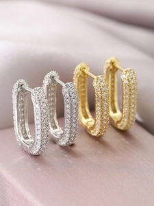 Detailed macro view of U-shaped silver and gold hoop earrings with pave cubic zirconia