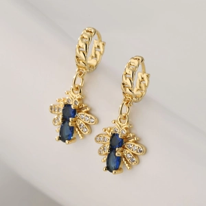Gold bee earrings with blue stones and zircon pavé wings on white background