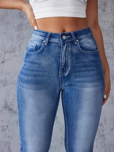 Detailed macro view of high-waisted distressed denim jeans showing cat-scratch texture