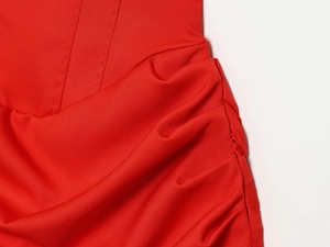 Gros plan d'une robe moulante rouge montrant les fronces et la texture du tissu tissé
