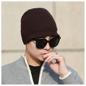 Detail showing thick dark brown knitted texture and short brim of the winter beanie cap