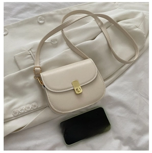Mini beige saddle bag with gold metal lock compared with phone for size perspective