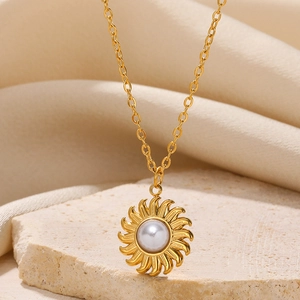 Macro shot of gold sunburst pendant with pearl on a textured stone and fabric background