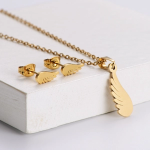Golden feather necklace and earrings jewelry set displayed on white geometric stones