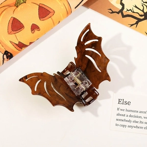 Macro detail of bat-shaped hair claw clip with tortoiseshell texture for Halloween styling