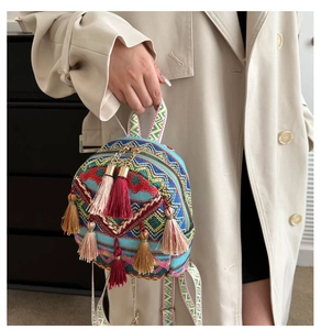 Detail of national style woven backpack with colorful fringe and metal zipper accents