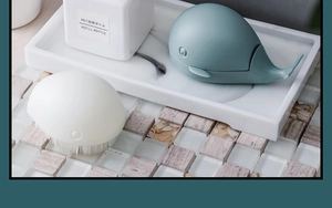 Close-up of whale-shaped laundry brushes on marble tray in a modern bathroom setting
