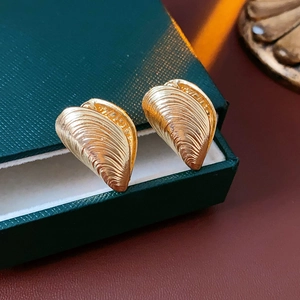 Macro shot of gold shell-shaped earrings with textured finish in a velvet jewelry box